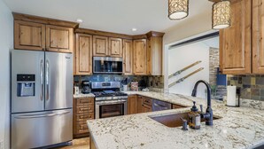 Una cocina moderna con gabinetes de madera, electrodomésticos de acero inoxidable y una encimera de granito.