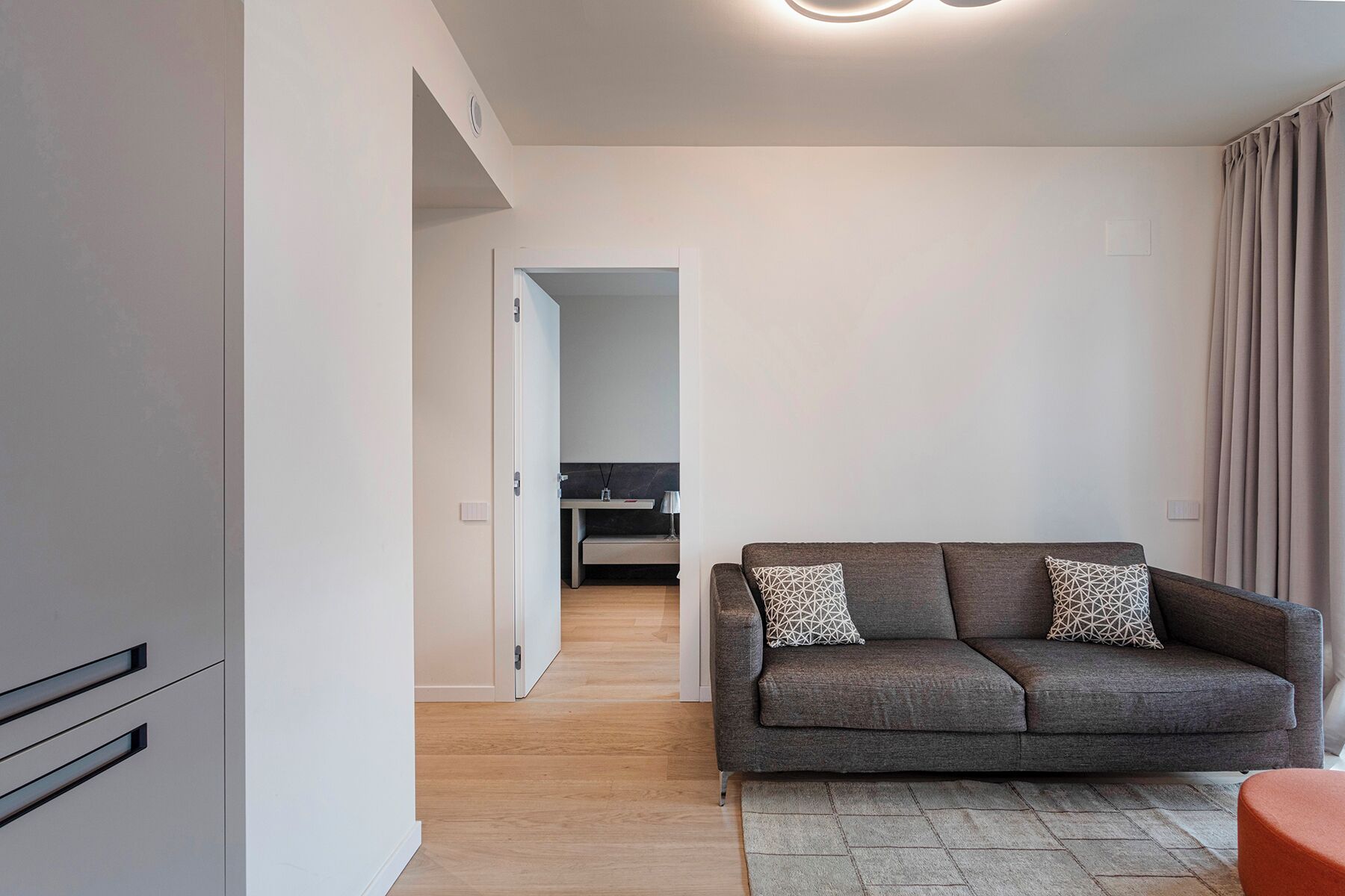 A modern living room with a grey sofa, a wooden floor, and a small table.