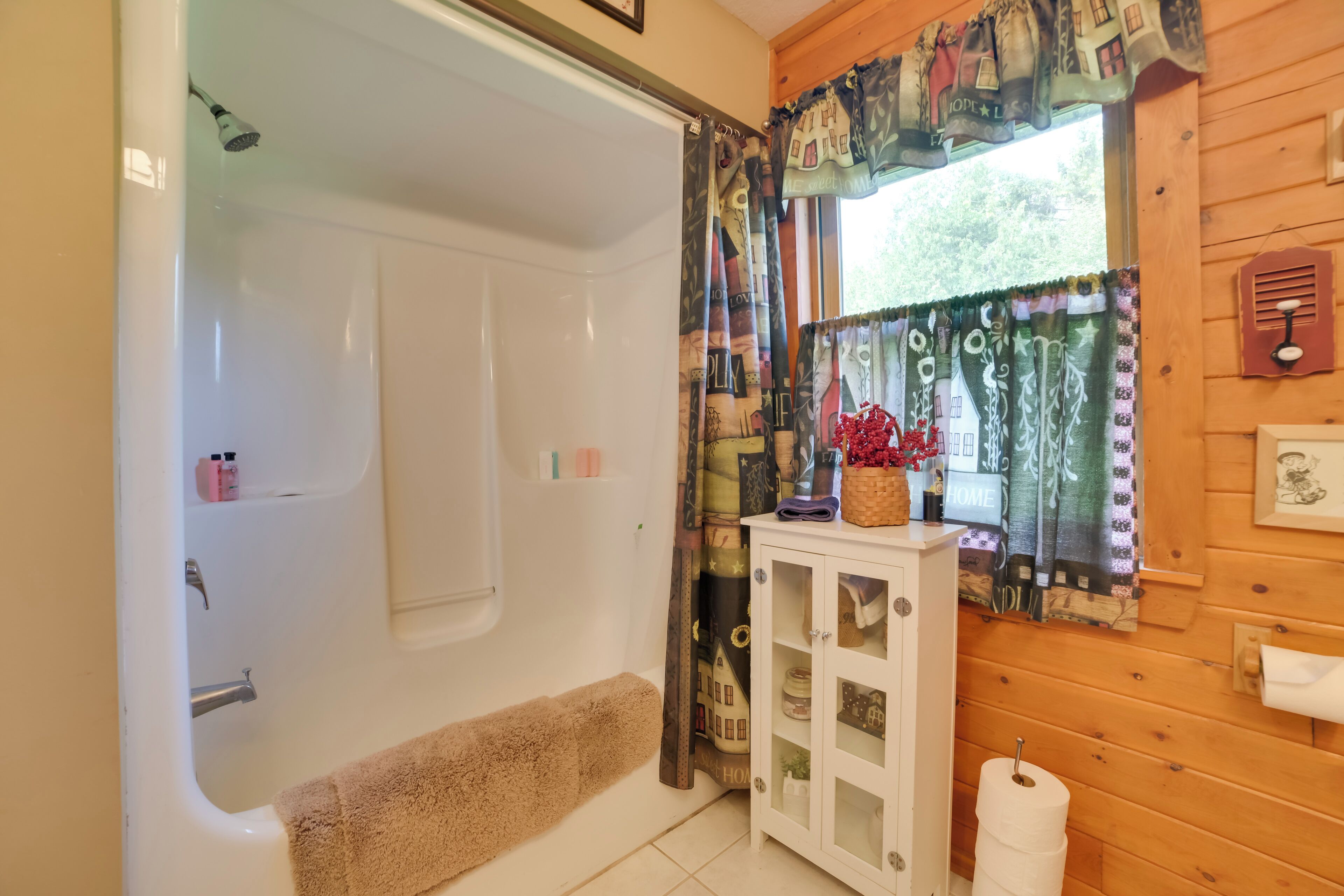 A bathroom with a bathtub, a shower, a toilet, and a cabinet with glass doors.