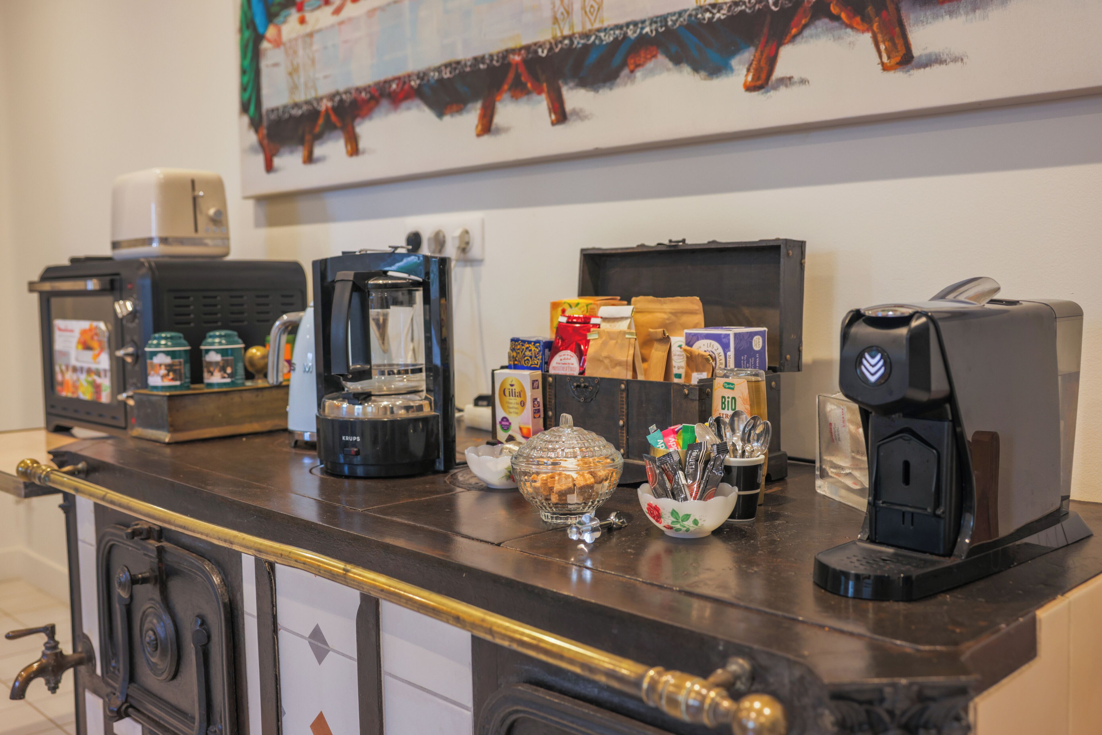 Zona de bar con máquinas de café, un recipiente de vidrio y diferentes alimentos.