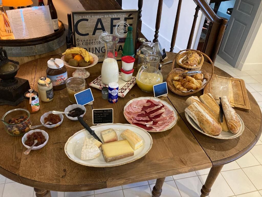 Une table de petit-déjeuner avec divers aliments, notamment du fromage, du pain et des condiments.