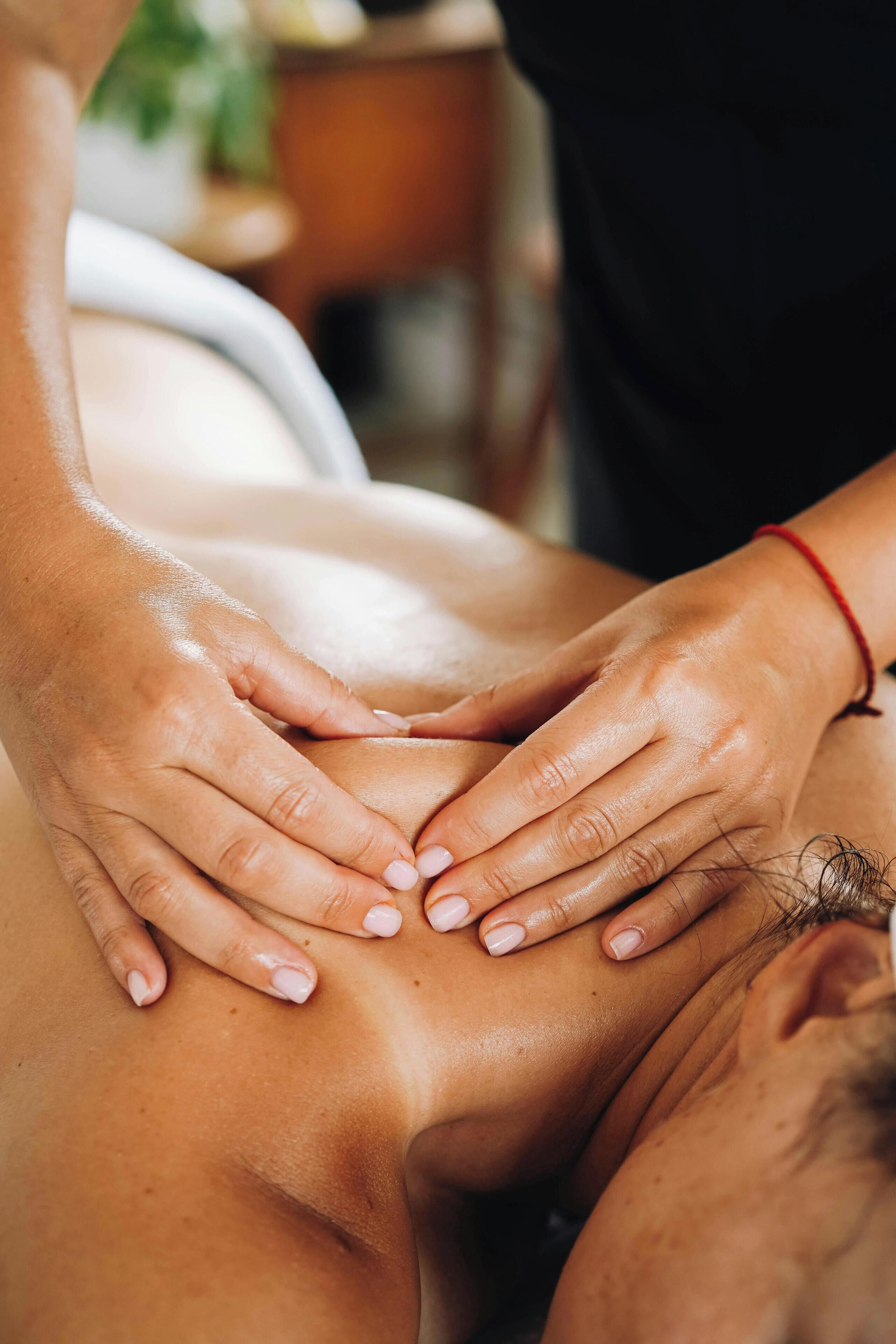 A close-up of hands performing a massage on a person's back.