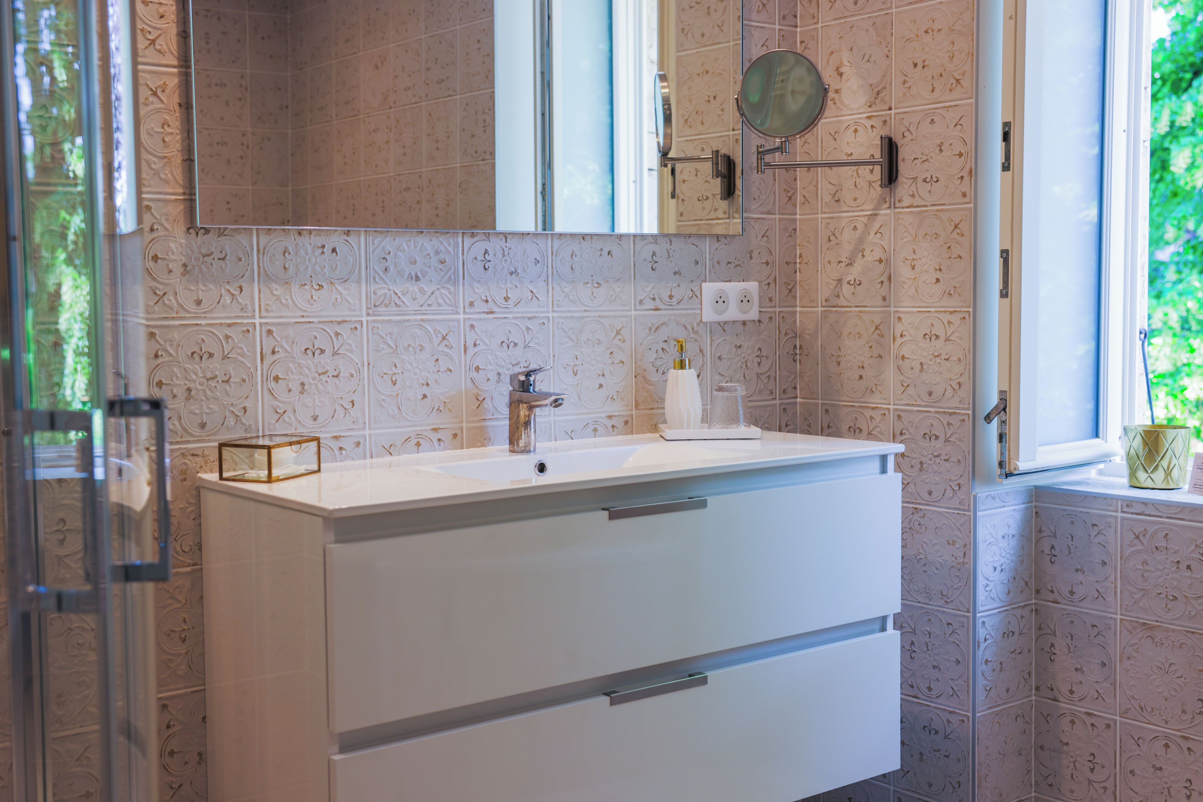 A bathroom with a white vanity, a mirror, and patterned tiles.
