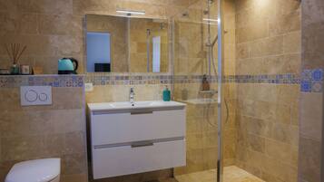 Un baño con ducha acristalada, un lavabo blanco y un inodoro.