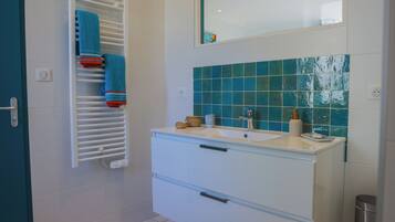 Une salle de bain avec un meuble-lavabo blanc, un miroir et un porte-serviettes avec des serviettes bleues.