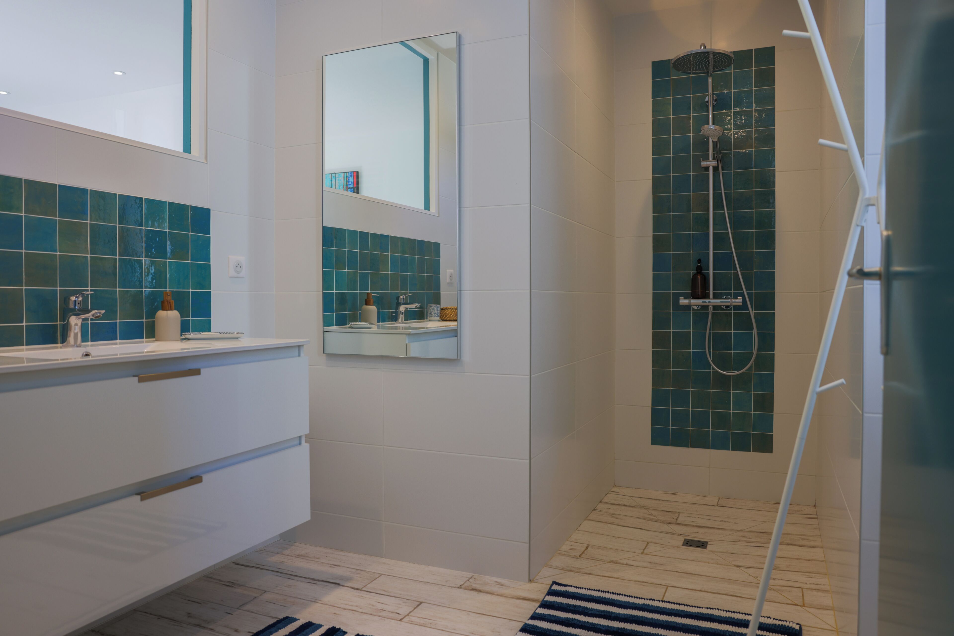 Un baño moderno con ducha, tocador con espejo y salpicadero de azulejos.