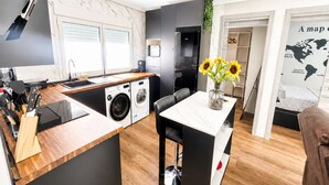 Eine moderne Küche mit integriertem Waschmaschine, einem Essbereich mit Tisch und Stühlen sowie einem großen Fenster.