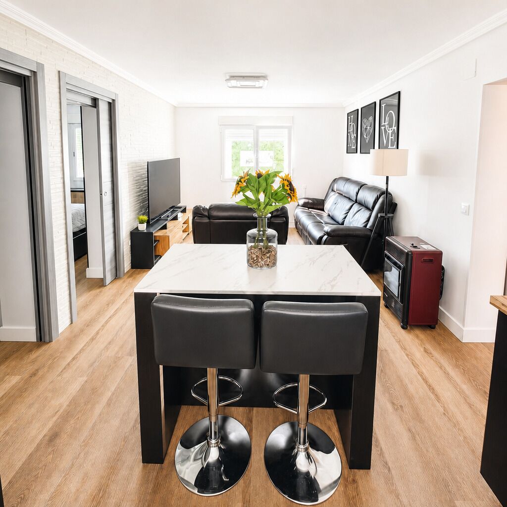 A modern living room with a dining table, black leather sofa, and a TV.
