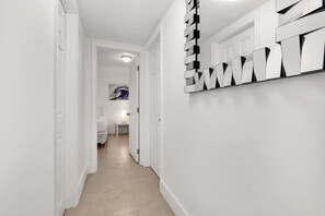 A hallway with white walls, a tiled floor, and a modern abstract art piece on the wall. - ° Cozy Private 2 BR Apt 5min to Brickell  8th st ° (Miami)