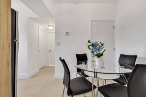 A modern dining area with a glass table, black chairs, and a potted plant. - ° Charming 2BR Apartment 5 min to Brickell ° (Miami)