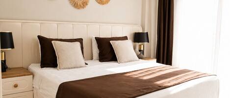 Un cuarto de hotel ordenado con una cama grande, dos mesitas de noche y decoración en la pared.