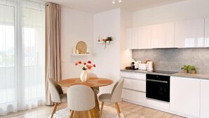 Una cocina moderna con armarios blancos, un horno negro y una encimera con cafetera.