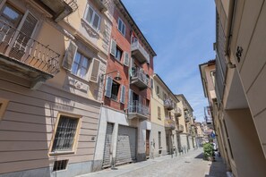 A narrow street lined with multi-story buildings, some with balconies and shutters. - Riva Verde by Wonderful Italy (Turin)