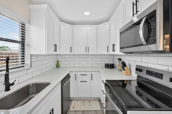 A modern kitchen with white cabinetry, a built-in microwave, and a dishwasher.