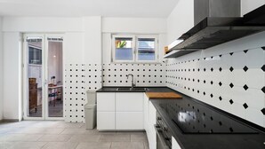 Une cuisine moderne avec un plan de travail noir, des armoires blanches et une fenêtre donnant sur un paysage agréable.