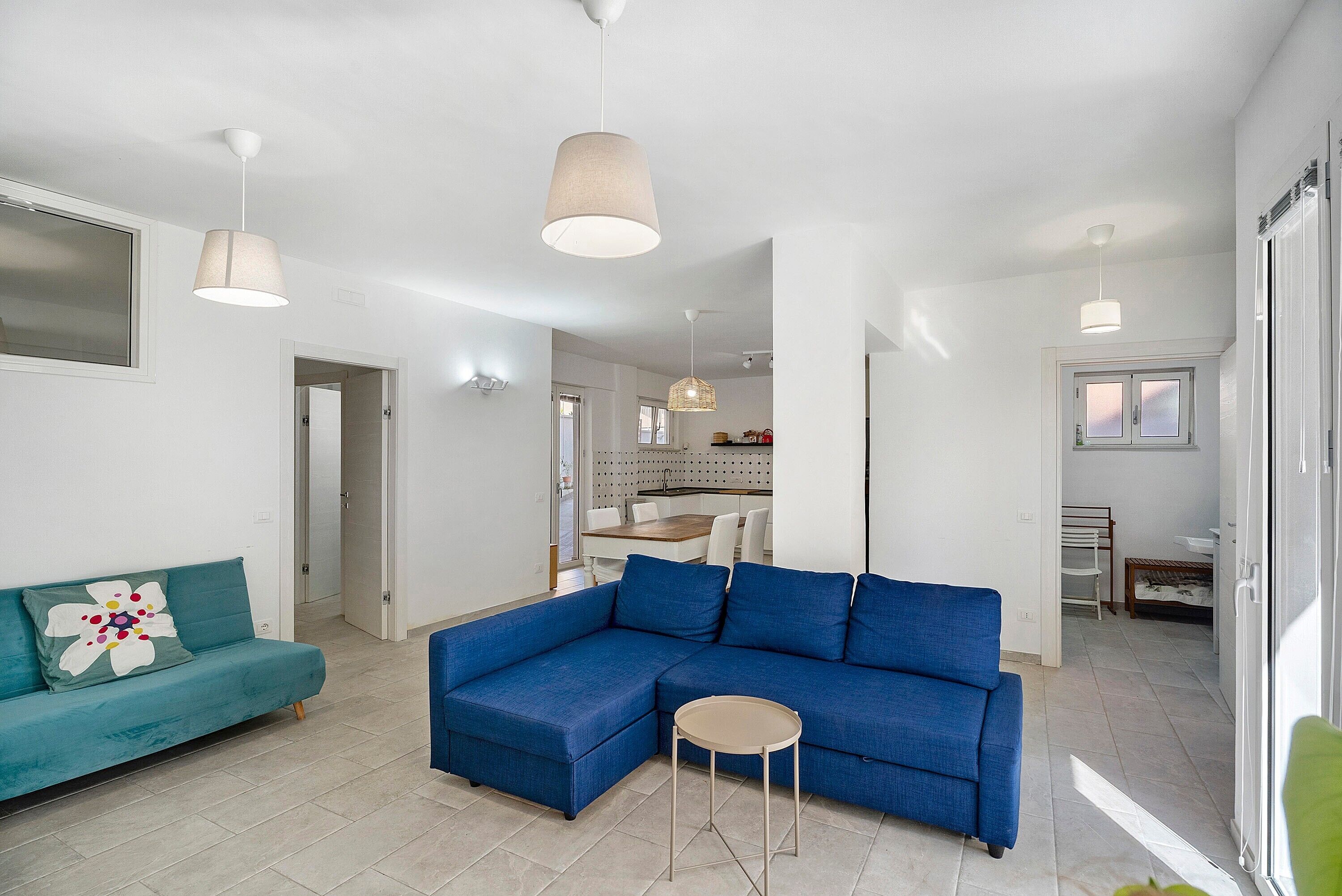 Una sala moderna con un sofá modular, una mesita redonda e iluminación colgante.