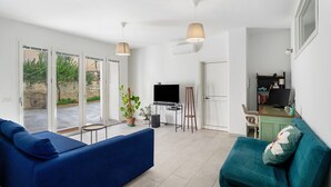 Un salon avec un canapé bleu, un canapé turquoise, un téléviseur et un bureau avec un ordinateur.