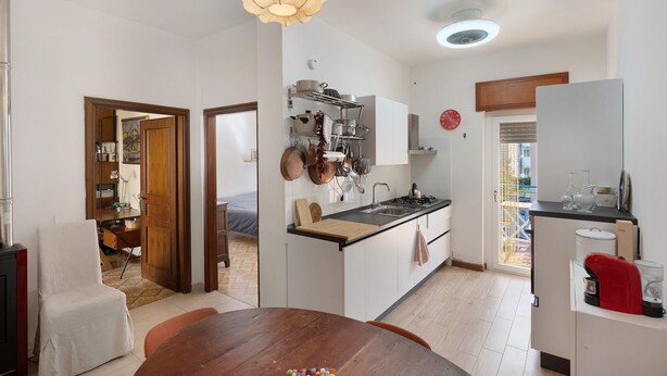 A modern kitchen with white cabinets, a wooden island, and a dining area with a wooden table. - Levante Apartment with Sea View, Wi-Fi and Air Conditioning (Agropoli)
