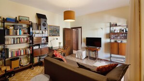 A living room with a sofa, a TV, a bookshelf, and a wooden cabinet. - Levante Apartment with Sea View, Wi-Fi and Air Conditioning (Agropoli)