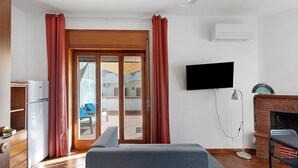 Ein Zimmer mit einem Bett, einem Fernseher, einem Kamin und Blick durch eine Glastür.