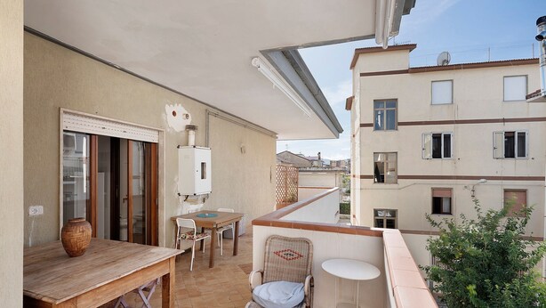 A balcony with a table, chairs, a wicker chair, a small round table, and a potted plant. - Apartment 'Ponente' with Sea View, Wi-Fi and Air Conditioning (Agropoli)