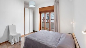 A bedroom with a bed, a chair, a window with curtains, and a ceiling light. - Apartment 'Ponente' with Sea View, Wi-Fi and Air Conditioning (Agropoli)
