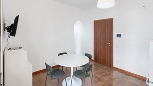 A room with a round table, four chairs, a white ceiling light, a wooden door, and a tiled floor. - Apartment 'Ponente' with Sea View, Wi-Fi and Air Conditioning (Agropoli)