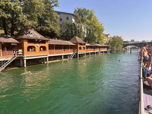 Eine Reihe von hölzernen Booten mit offenen Seiten liegt an einem Fluss festgemacht.