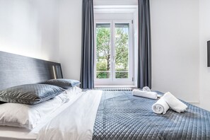 A neatly made bed with a headboard, pillows, and a rolled towel on a bed with a quilted pattern. - Delta City Hotels - Self check (Zürich)