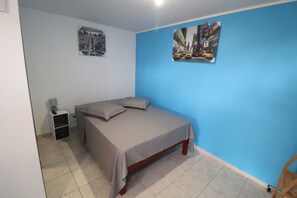 A bedroom with a bed, a nightstand, and two wall art pieces. - Les Gites de lUnion (Les Abymes)