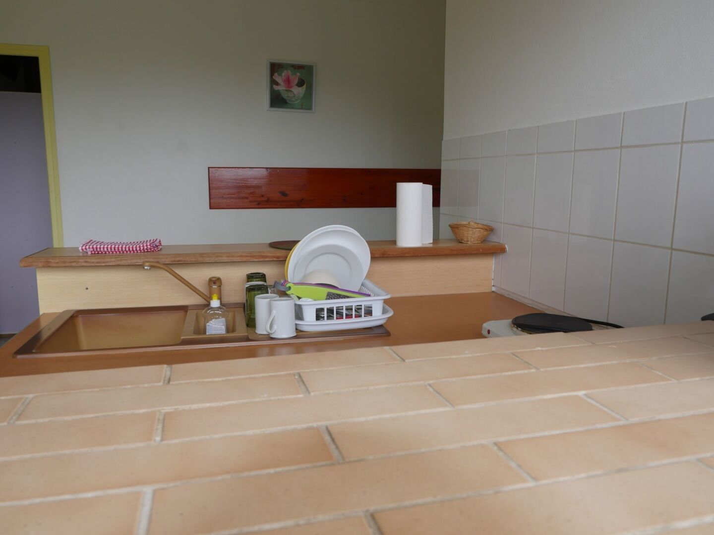 Una cucina con lavello, piano di lavoro e un piccolo ripiano con un cesto.