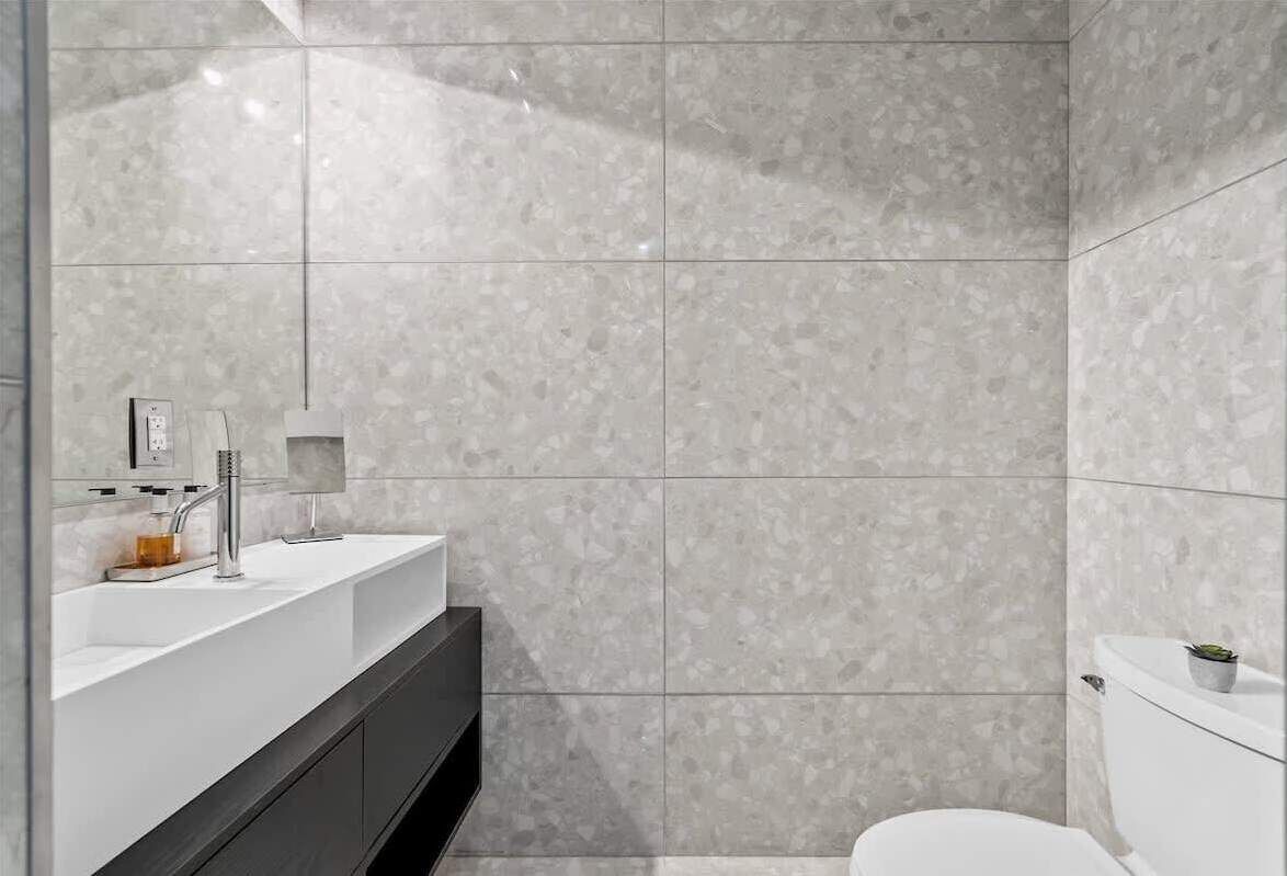 Une salle de bain moderne avec un lavabo blanc, un meuble sombre et des toilettes.
