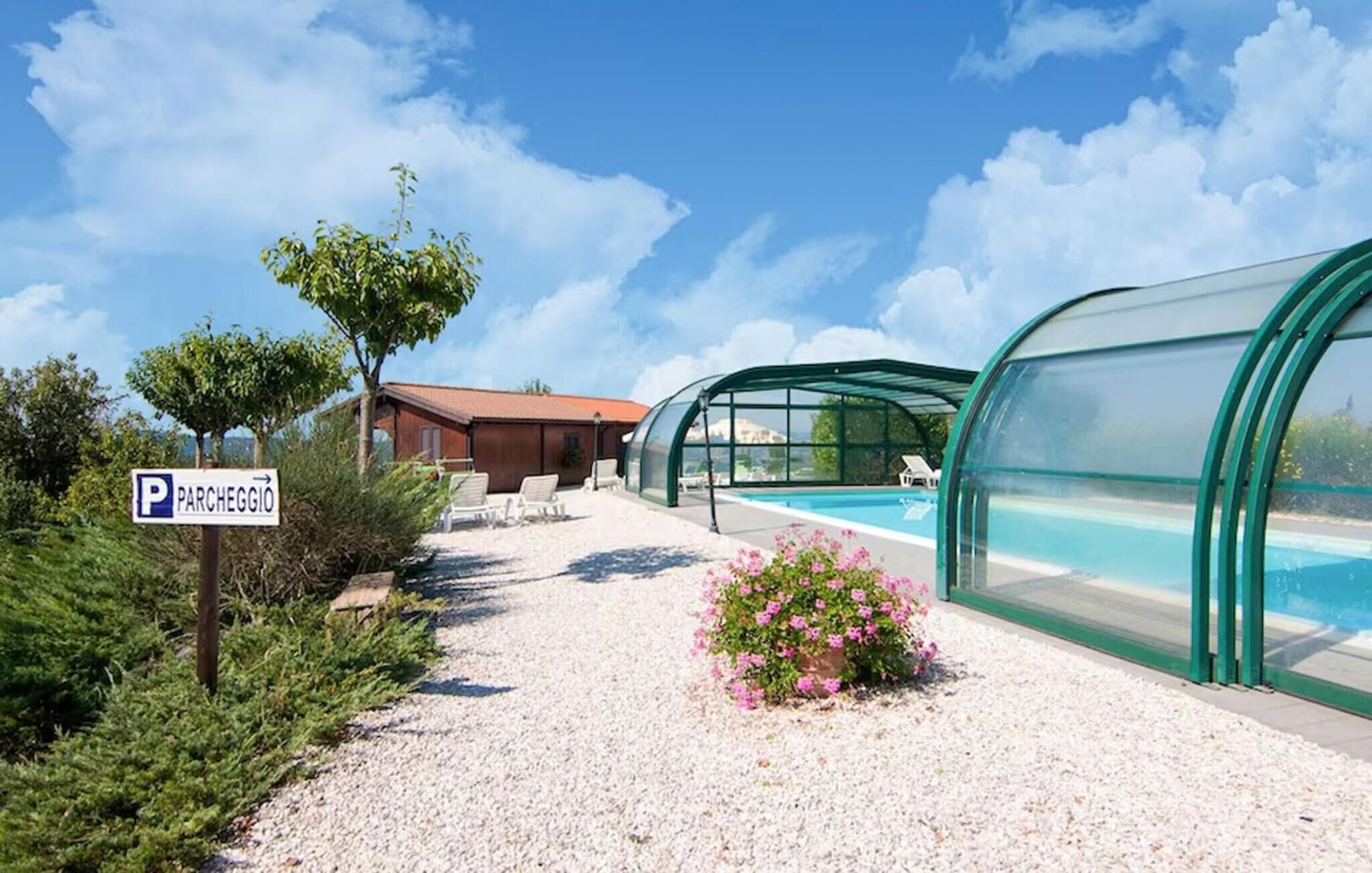 A pool area with a covered structure, a gravel path, and a sign indicating a parking area.