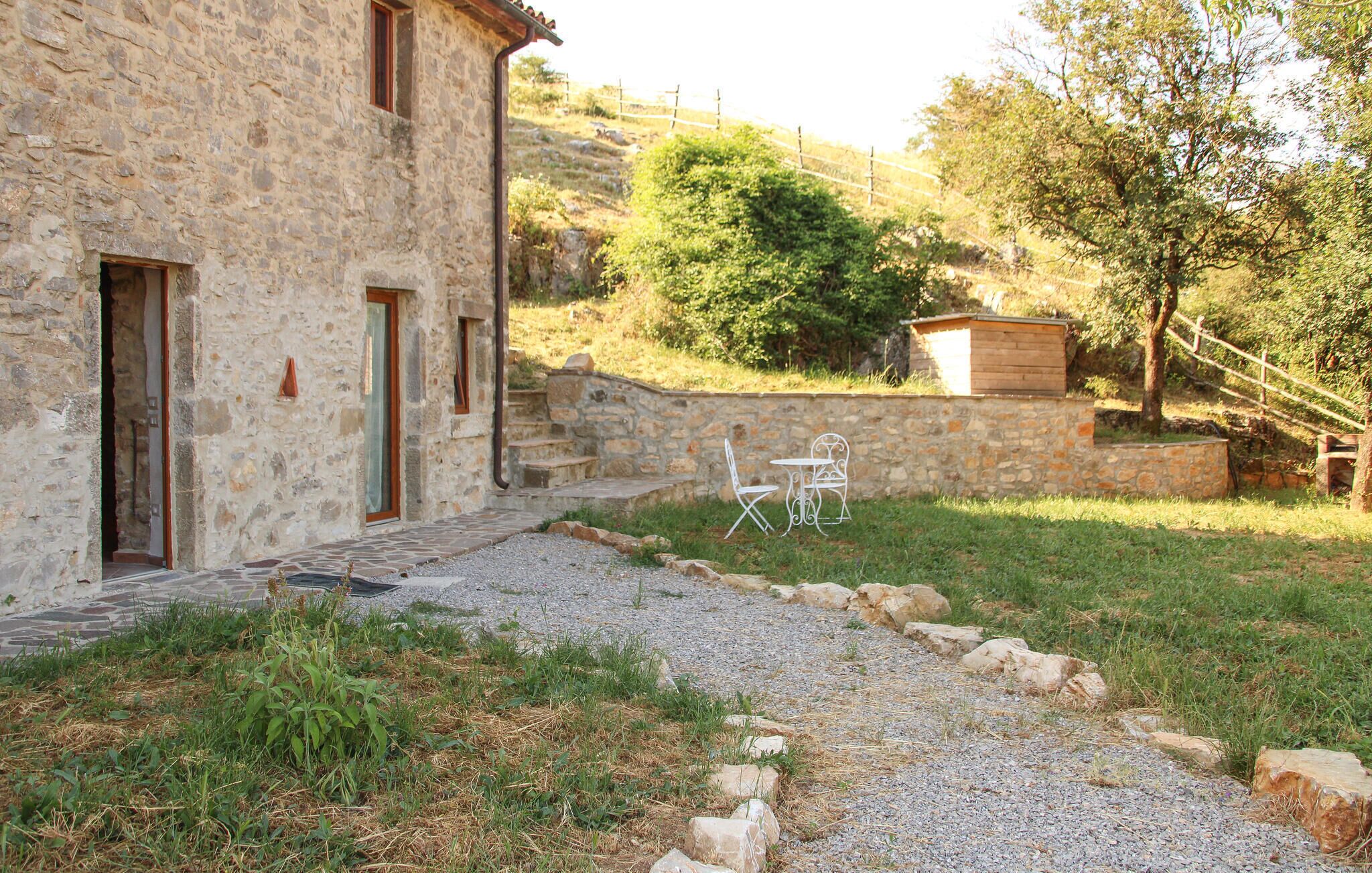 A stone building with a gravel pathway leading to outdoor seating.