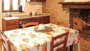 Una cucina accogliente con un tavolo da pranzo per due, con un rustico camino e mobili in legno.