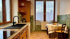 A kitchen with a sink, wooden cabinets, a window, and a table with a chair. - 1 bedroom amazing home in Nanteuil-en-Vallée (Nanteuil-en-Vallée)