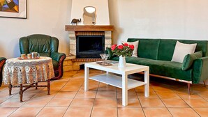 A living room with a fireplace, a green sofa, a coffee table, a chair, and a table with a lace tablecloth. - 1 bedroom amazing home in Nanteuil-en-Vallée (Nanteuil-en-Vallée)