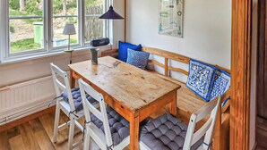 A cozy room with a wooden table and chairs, a bench with blue cushions, a lamp, and a window with a view of greenery. - Lovely home in Gränna with WiFi (Gränna)