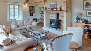A cozy living room with a fireplace, a sofa, a coffee table, and a bookshelf. - Superbe maison avec piscine (Montgesty)