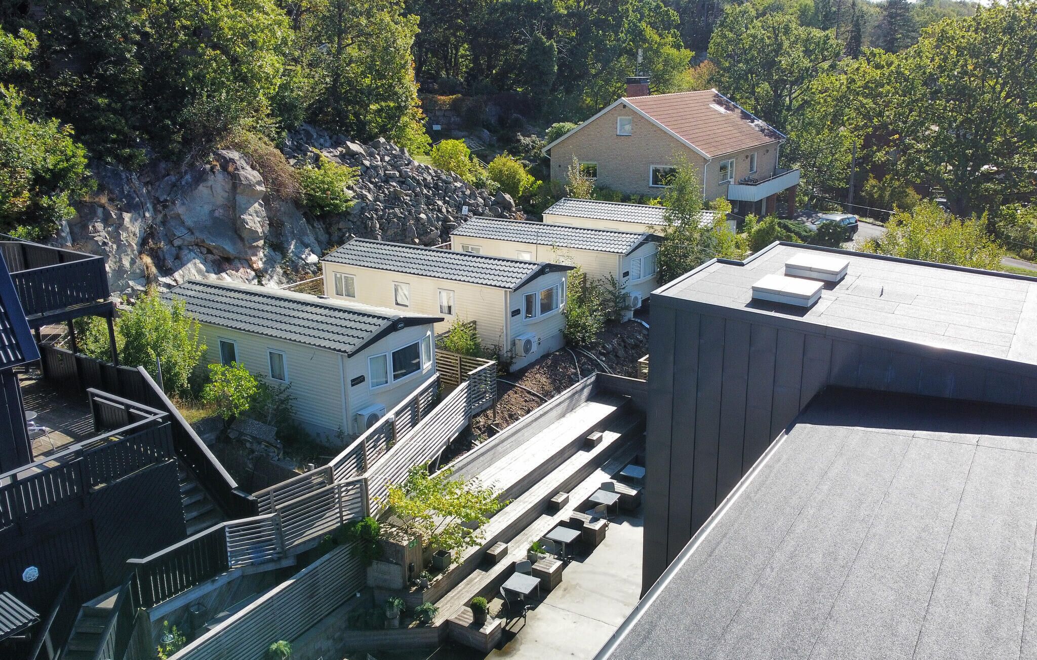 A residential area with multiple houses, a rocky hillside, and a large building with a flat roof.