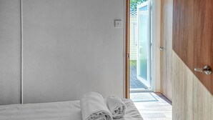 A bedroom with a bed, a wooden door, and a view of a patio. - Beautiful home in Göteborgs with WiFi (Göteborgs)