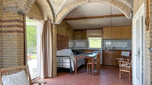 Una cocina rústica con paredes de ladrillo, una mesa de madera y una cama con cabecera de mimbre.