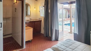 Habitación de hotel con cama, baño con lavamanos y vista a una piscina.