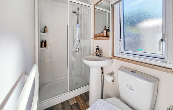 A modern bathroom with a glass shower enclosure, a white sink, and a toilet.
