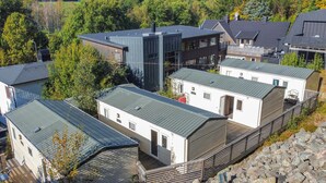 A cluster of modern cabins with metal roofs, surrounded by trees and rocky terrain. - 2 bedroom lovely home in Göteborgs (Göteborgs)