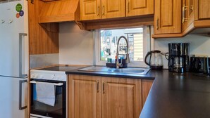 Une cuisine compacte avec des meubles en bois, un four encastré, un évier avec un robinet et une machine à café.