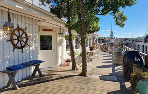 Une terrasse en bois avec un banc, une décoration en forme de roue de navire et un espace barbecue.