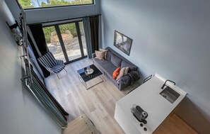 Una sala moderna con un sofá gris, un sillón a rayas y una mesa de comedor.