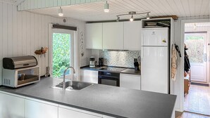 Eine moderne Küche mit weißen Schränken, einem Einbauofen, einer Kaffeemaschine und einem Kühlschrank.