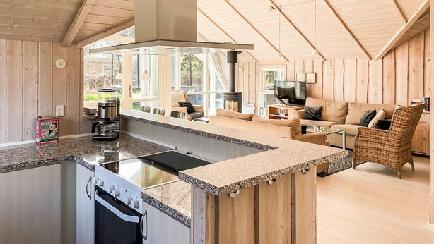 Una cocina moderna con una isla central, una zona de comedor con sofá y un amplio ventanal que proporciona luz natural.